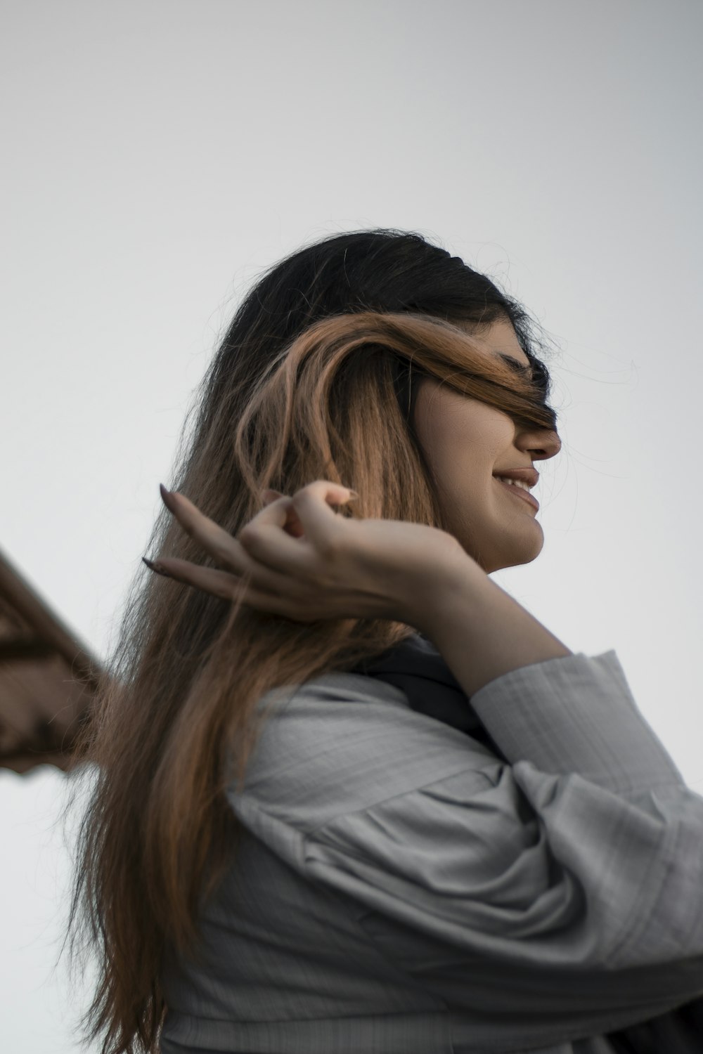 woman in gray long sleeve shirt covering her face with her hair