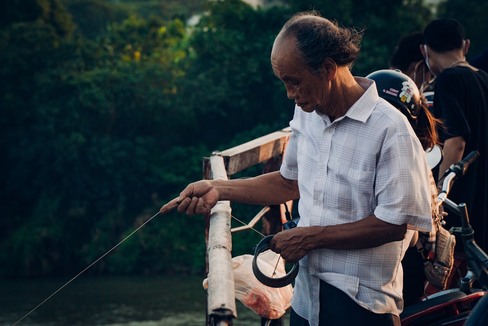 man in blue and white plaid button up shirt holding fishing rod during daytime