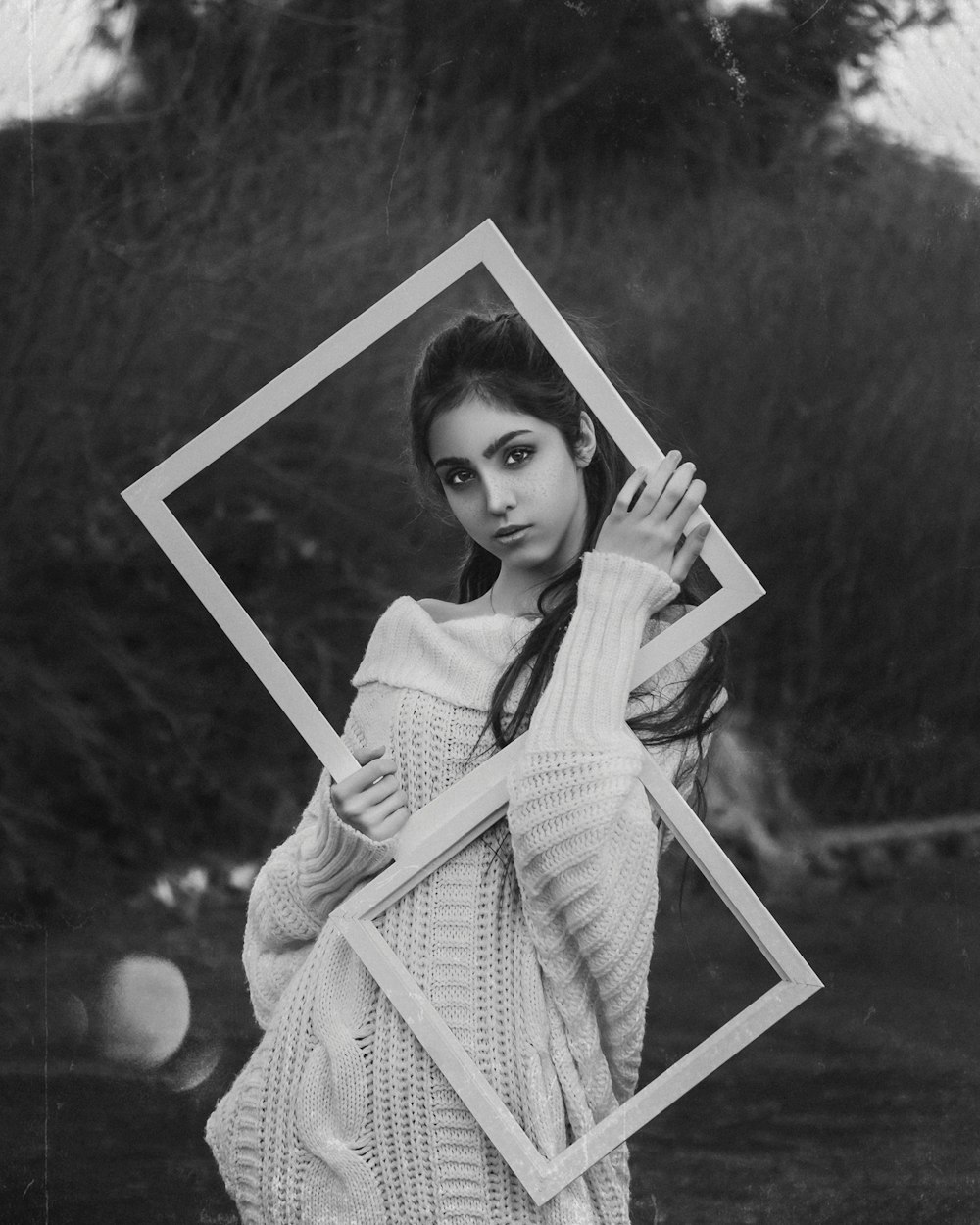 grayscale photo of girl in dress holding photo frame