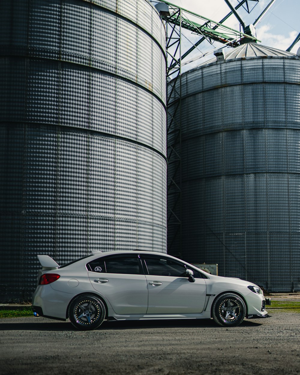 white coupe parked beside gray metal building