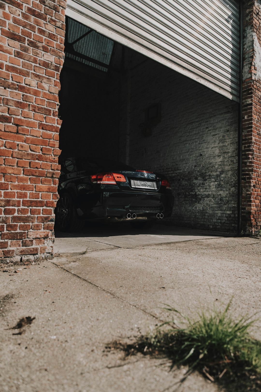 black car parked beside brown brick wall