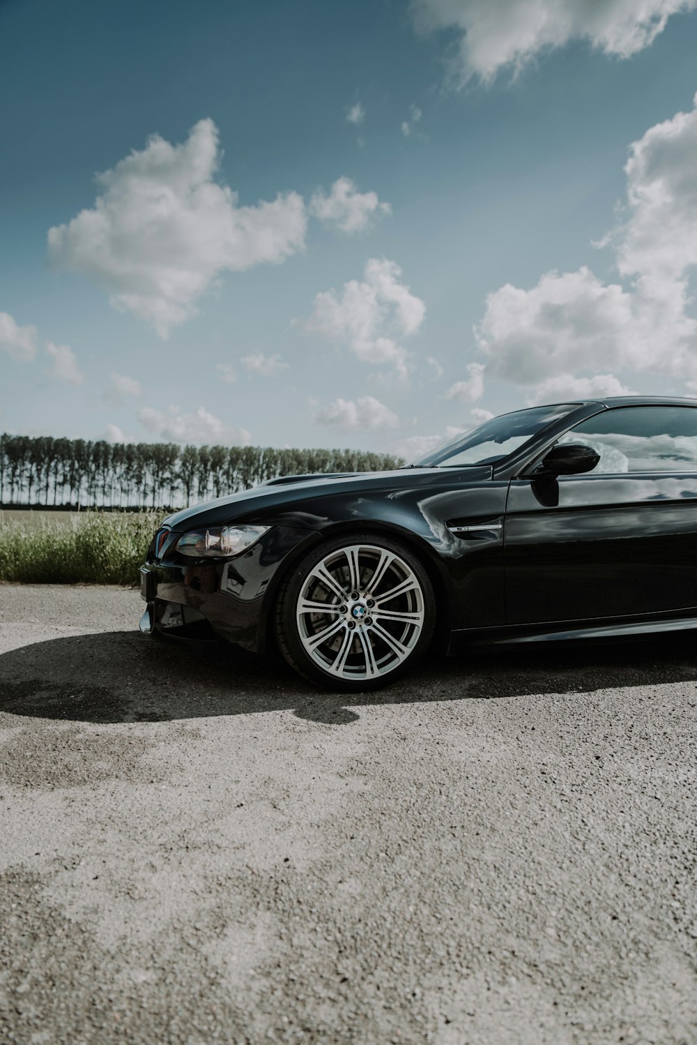 black coupe on gray sand under blue sky during daytime