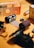 Several film canisters and a strip of exposed film lie on a surface. The items include a mix of film packaging and rolls of both color and black-and-white film. The background is a soft orange color, creating a warm tone for the image.