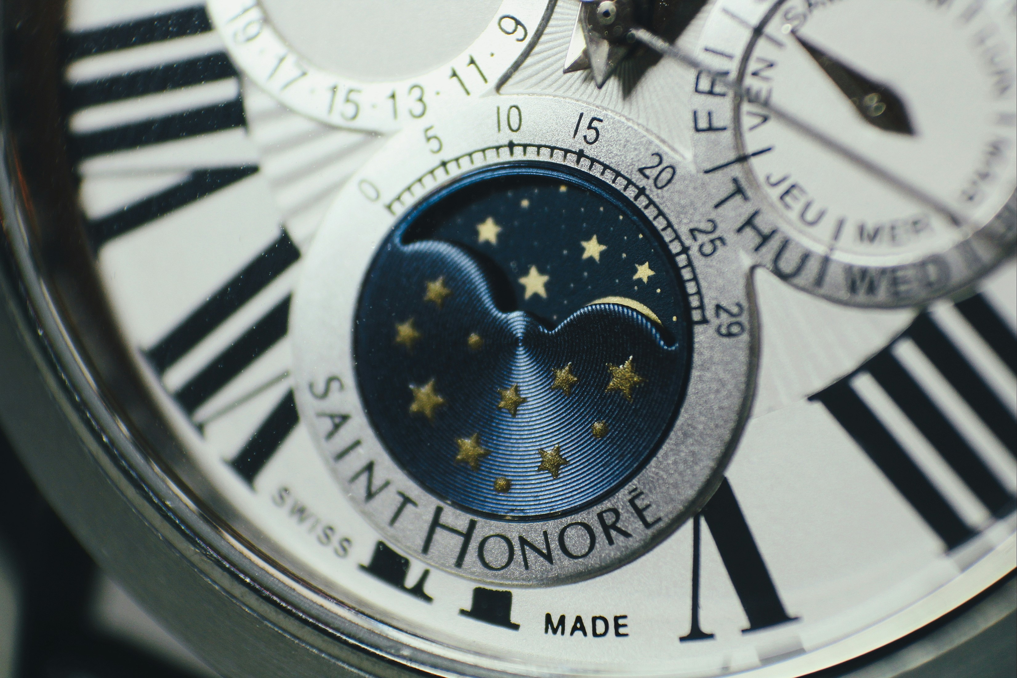 Close-up of a perpetual calendar wristwatch dial showing day, date, and moon phase
