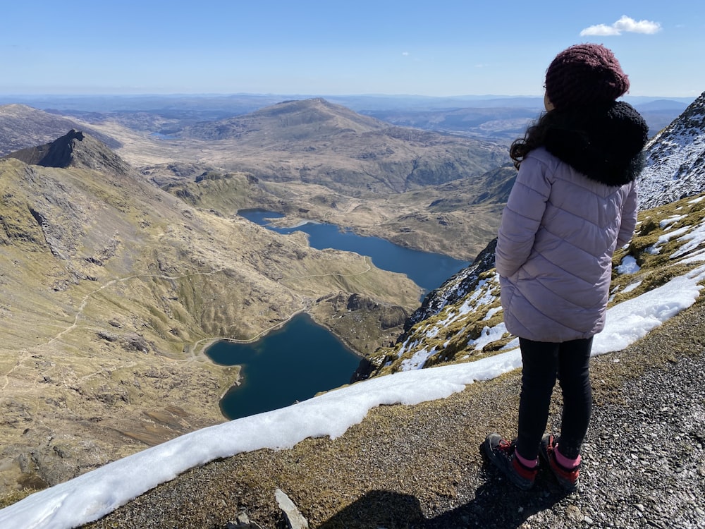 woman in black jacket and black pants standing on rocky hill during daytime