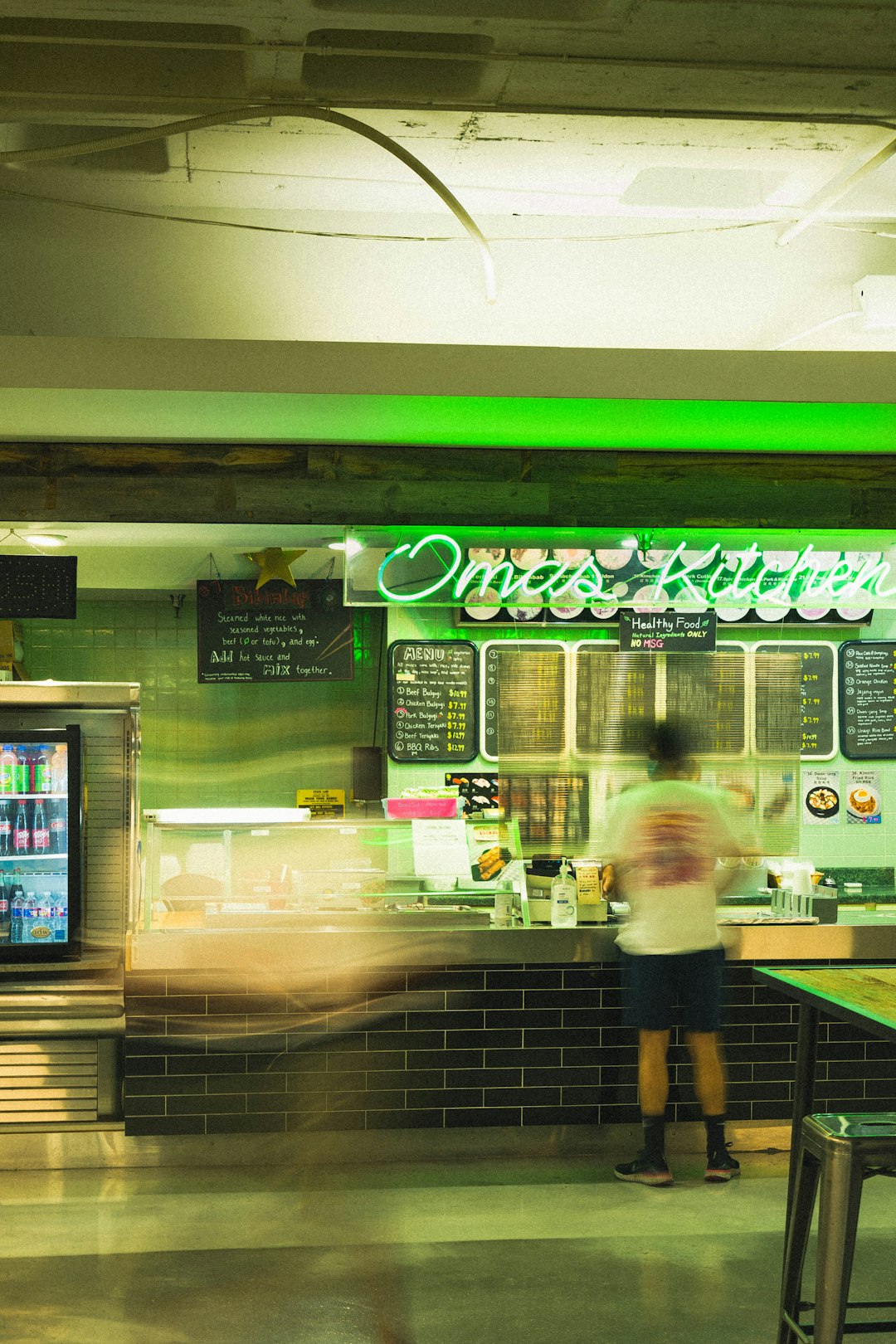 woman in pink shirt standing in front of green and white store