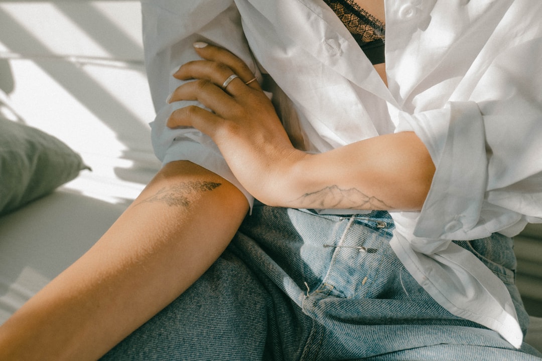 woman in white button up shirt and blue denim shorts sitting on white textile