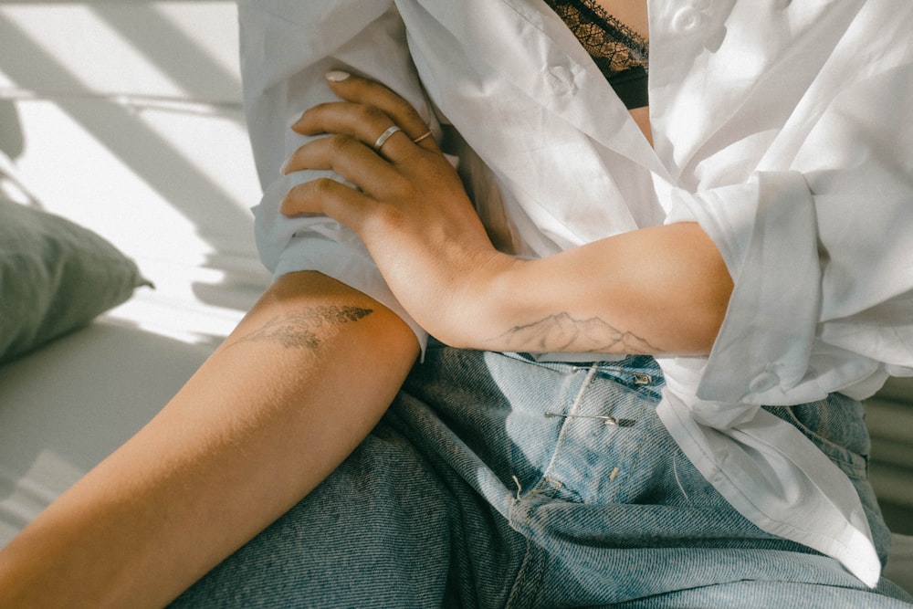 woman in white button up shirt and blue denim shorts sitting on white textile