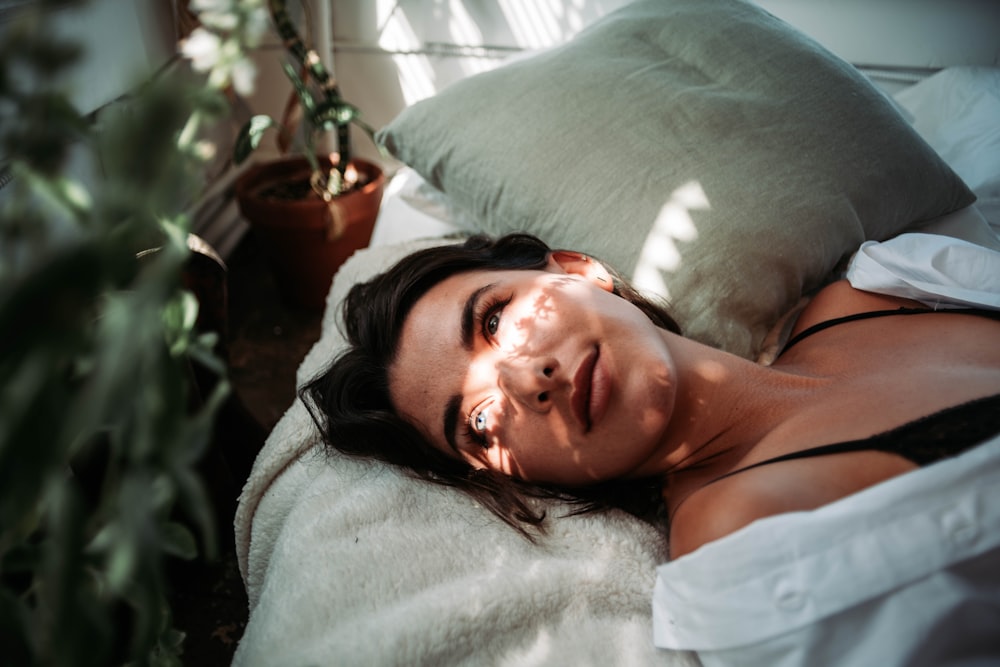 woman in white tank top lying on bed