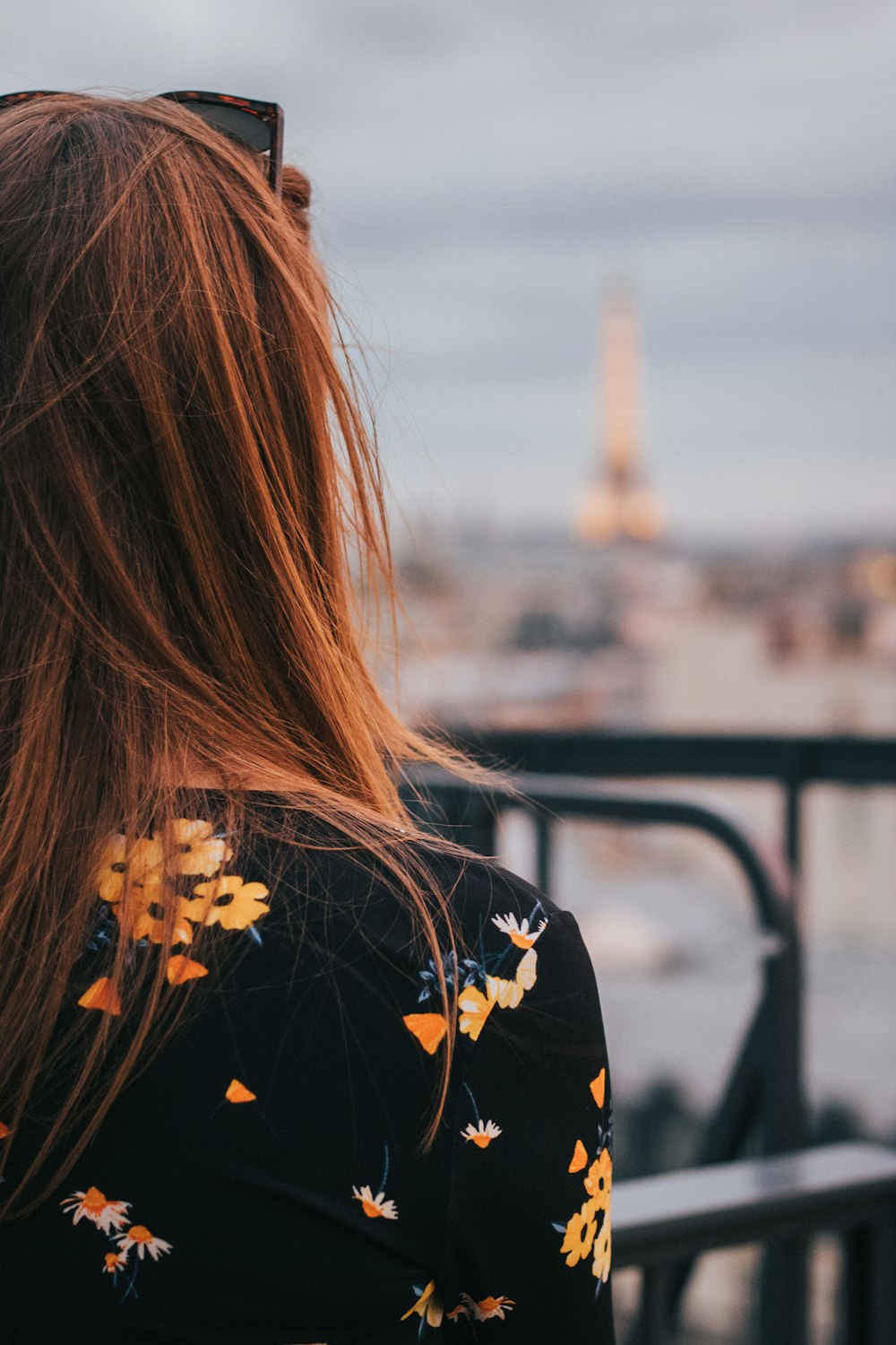 Donna in camicia floreale nera e gialla in piedi vicino alle ringhiere durante il giorno