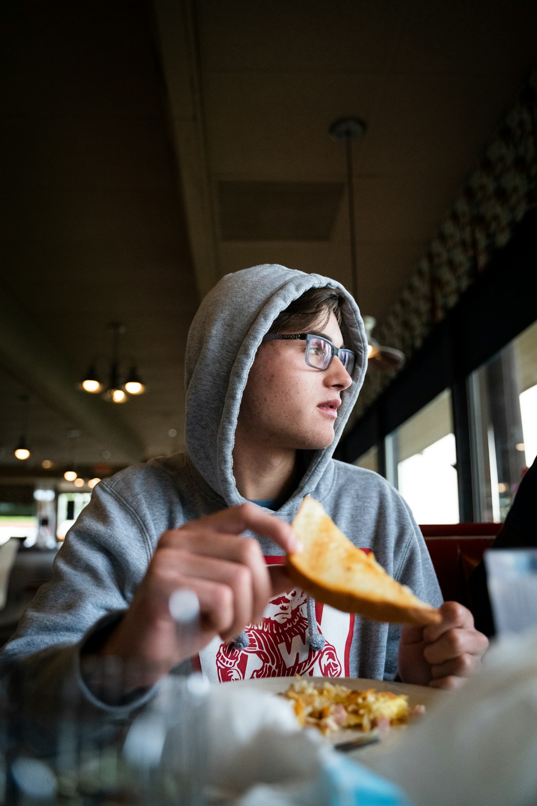 person in gray hoodie holding bread