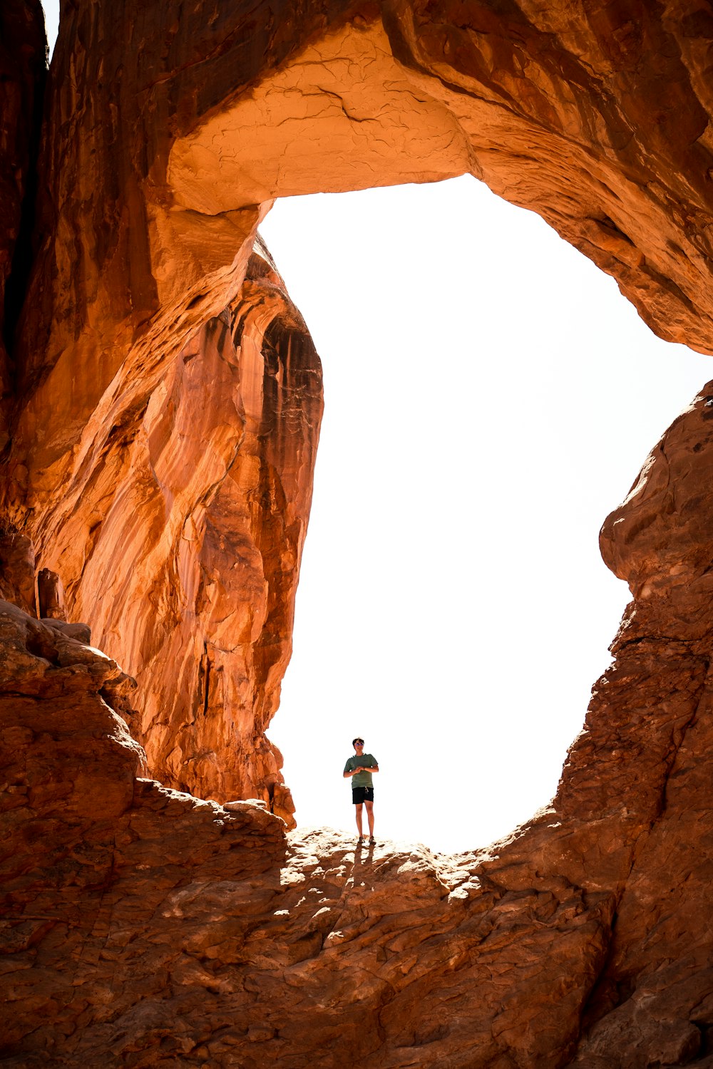 man in black jacket standing on brown rock formation during daytime