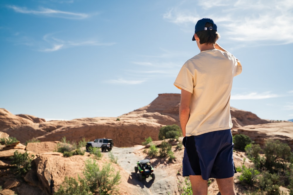 man in white crew neck t-shirt and blue shorts standing on brown rock formation during