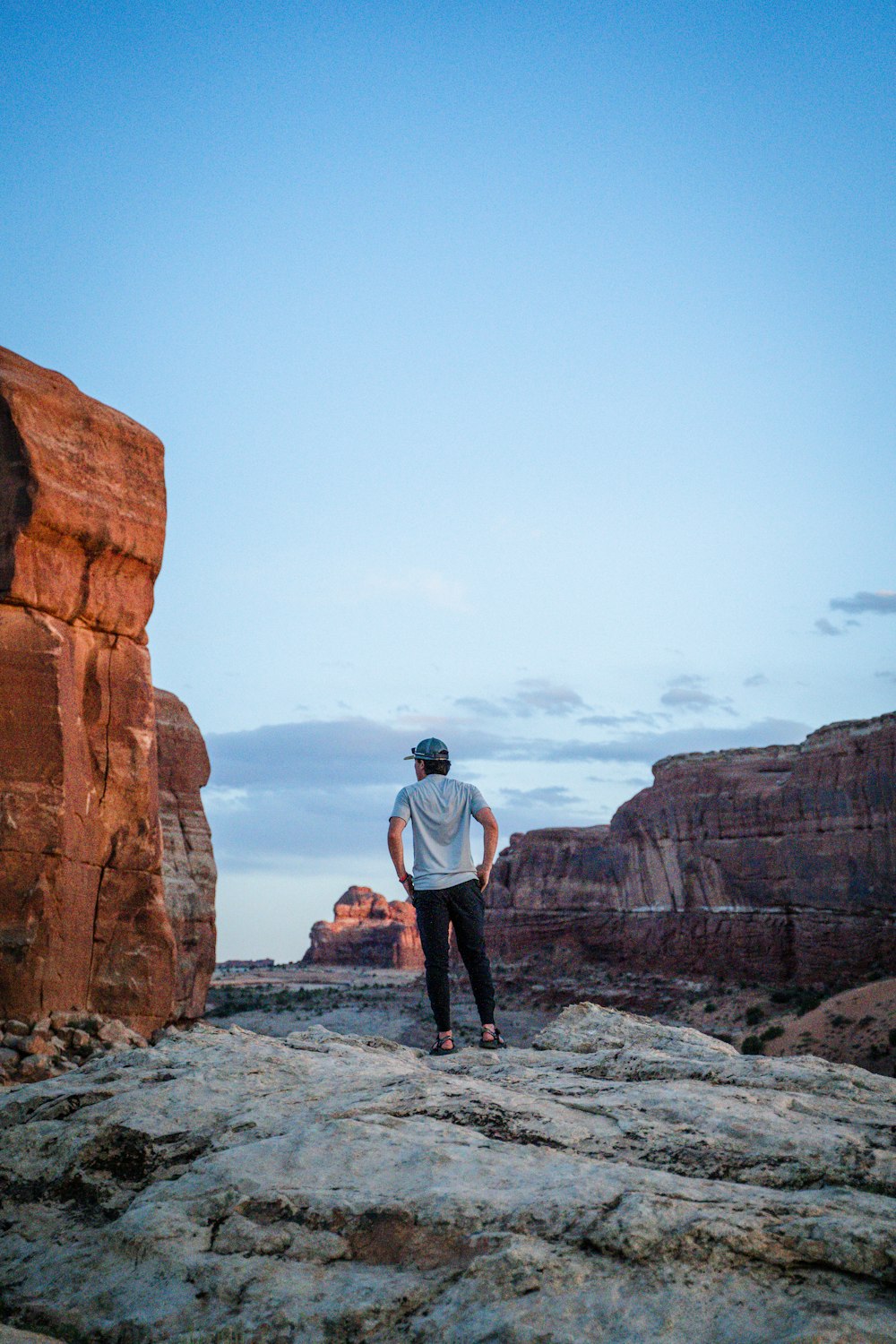 man in white shirt standing on rock formation during daytime