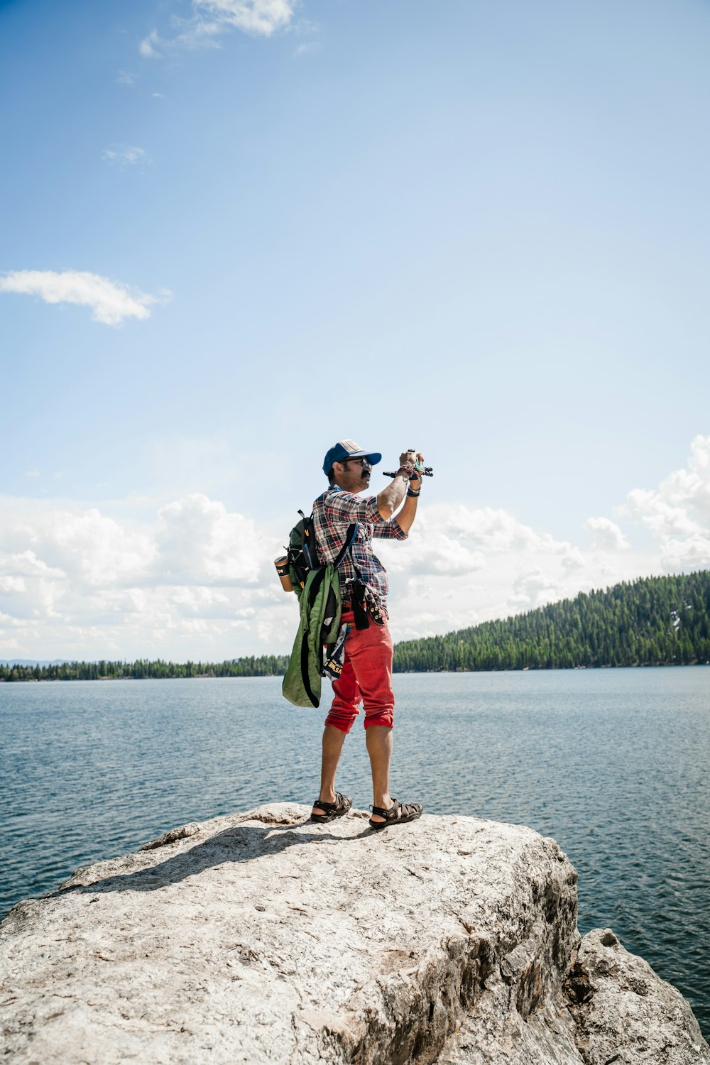 man in green shorts standing on rock near body of water during daytime