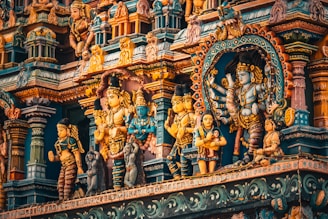 A richly detailed facade of a Hindu temple features an array of colorful, ornate sculptures depicting various deities and figures. The intricate carvings and vibrant colors create a mesmerizing visual effect, showcasing traditional Indian art styles.