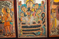 A traditional Indian painting depicting mythological figures and serpentine forms. Intricate patterns and vibrant colors are prominent, featuring deities seated on a coiled serpent, surrounded by smaller figures and mystical motifs.