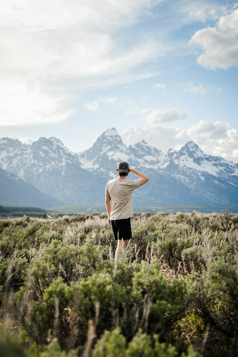 man in white t-shirt and black shorts standing on green grass field during daytime