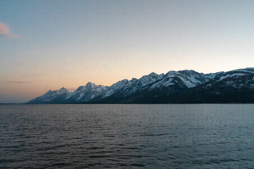 snow covered mountain near body of water during daytime