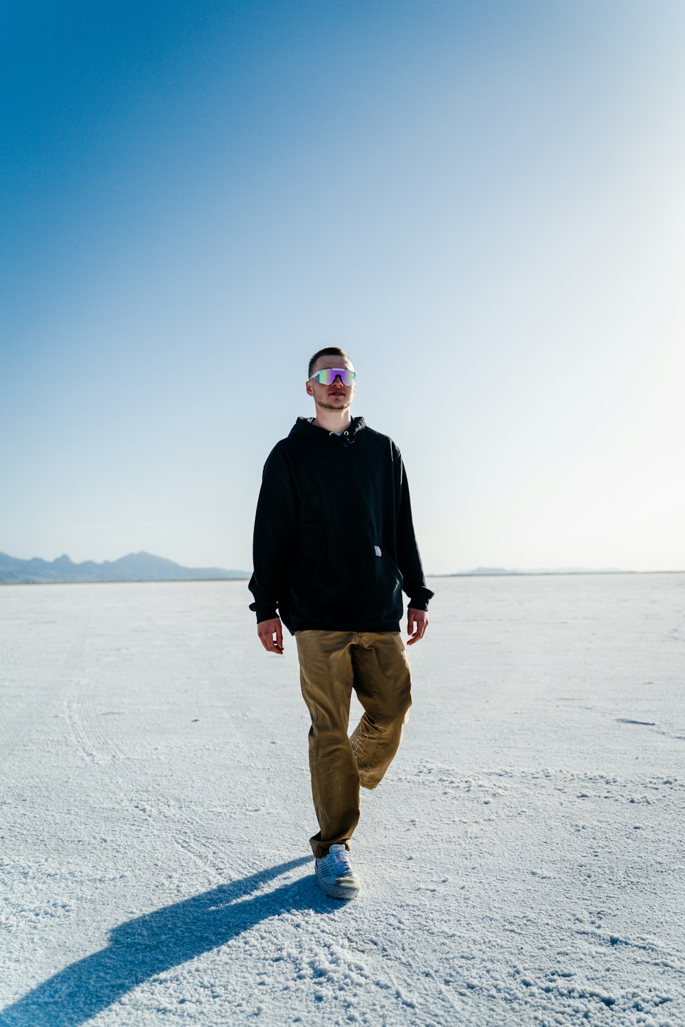 man in black jacket and brown pants standing on white sand during daytime