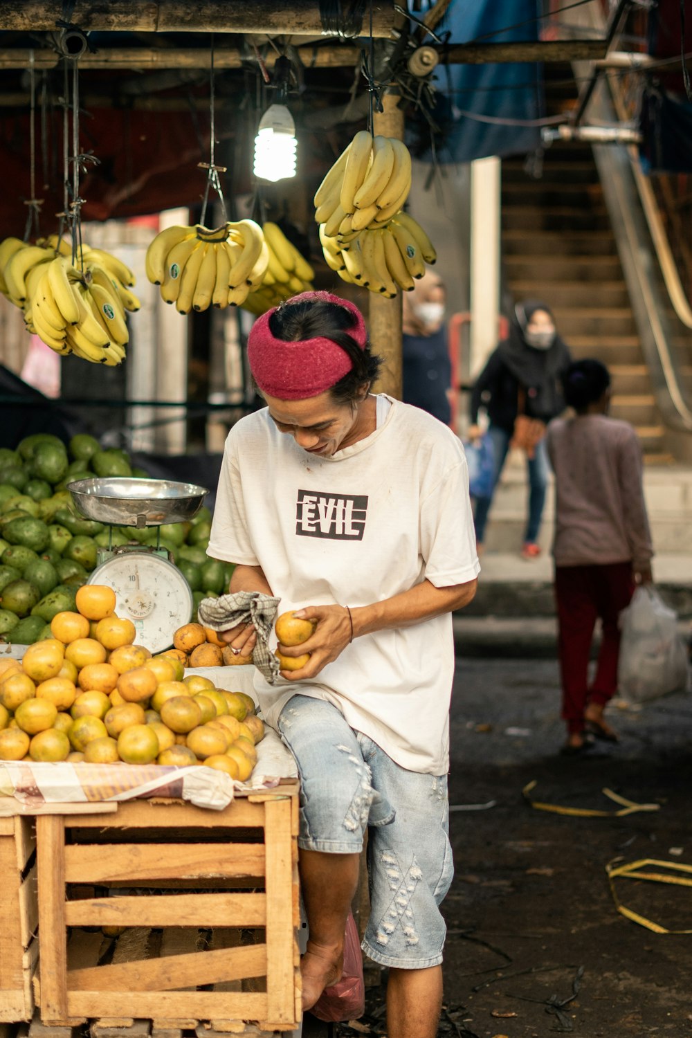 man in white shirt and red knit cap holding yellow banana fruit