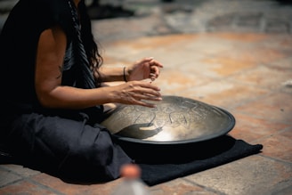 woman in black dress sitting drumming