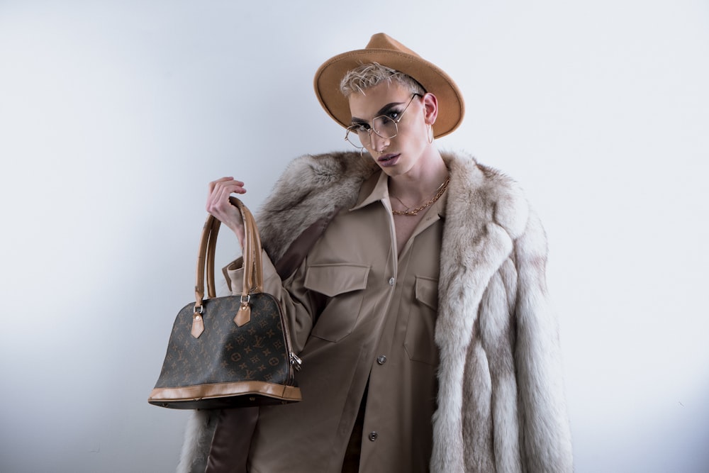 woman in brown coat wearing brown hat and brown leather shoulder bag