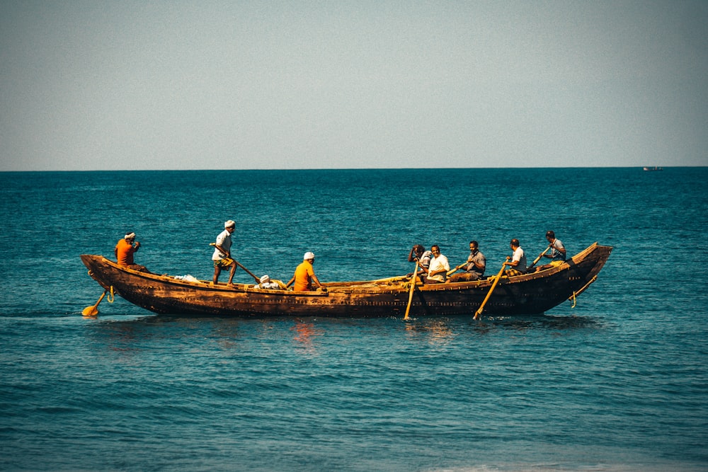 people riding on brown boat on sea during daytime