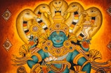 A traditional Indian artwork depicting a deity with blue skin adorned in intricate golden jewelry and ornaments, surrounded by multiple hooded cobras. The background features warm shades of orange and gold, adding to the mythical and spiritual ambiance.