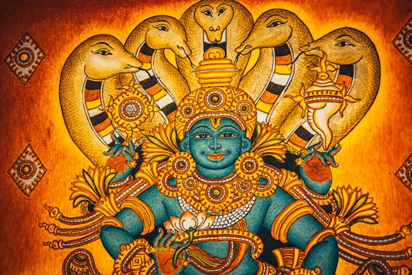 A traditional Indian artwork depicting a deity with blue skin adorned in intricate golden jewelry and ornaments, surrounded by multiple hooded cobras. The background features warm shades of orange and gold, adding to the mythical and spiritual ambiance.