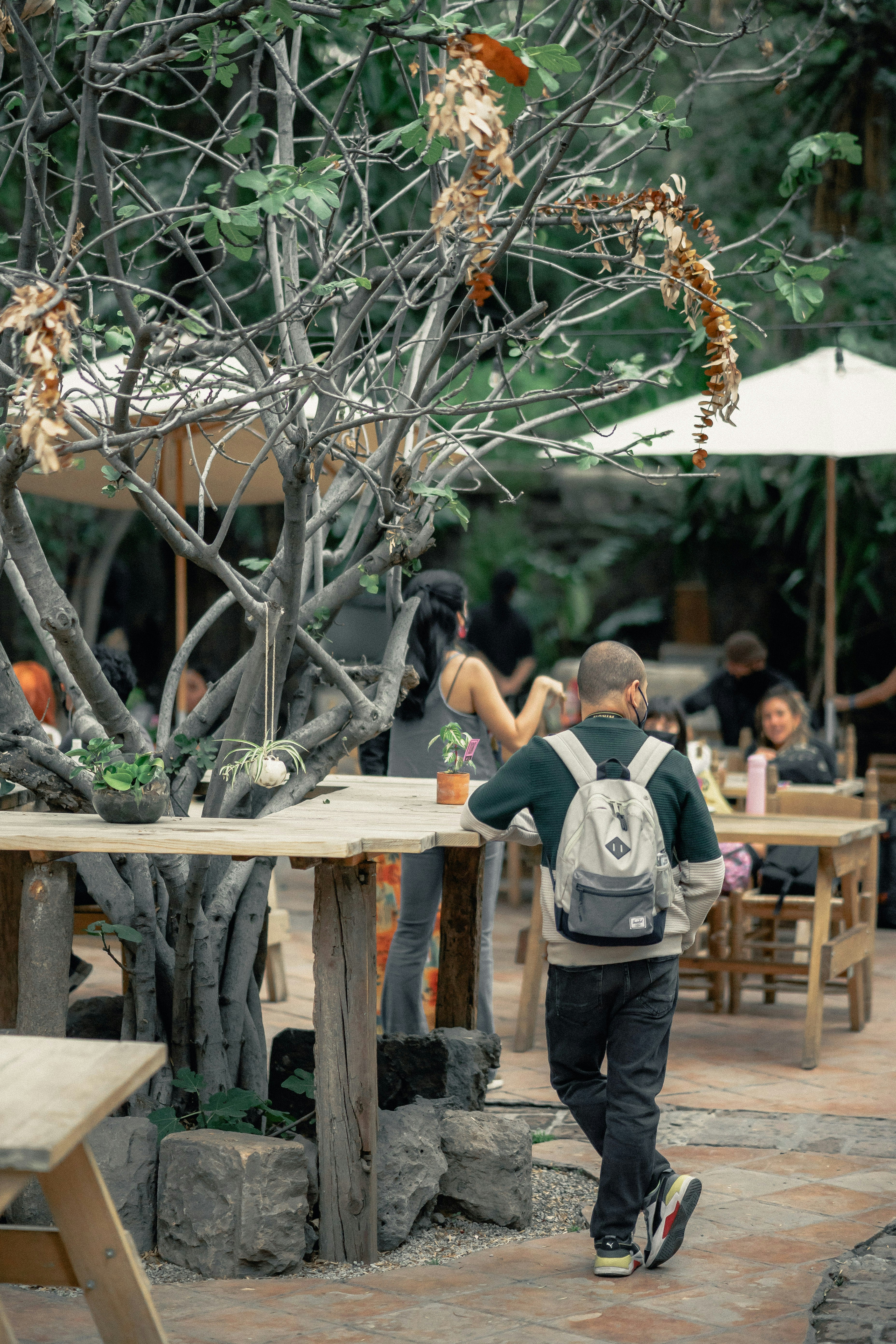 man in blue and white striped polo shirt and gray pants standing beside brown wooden table