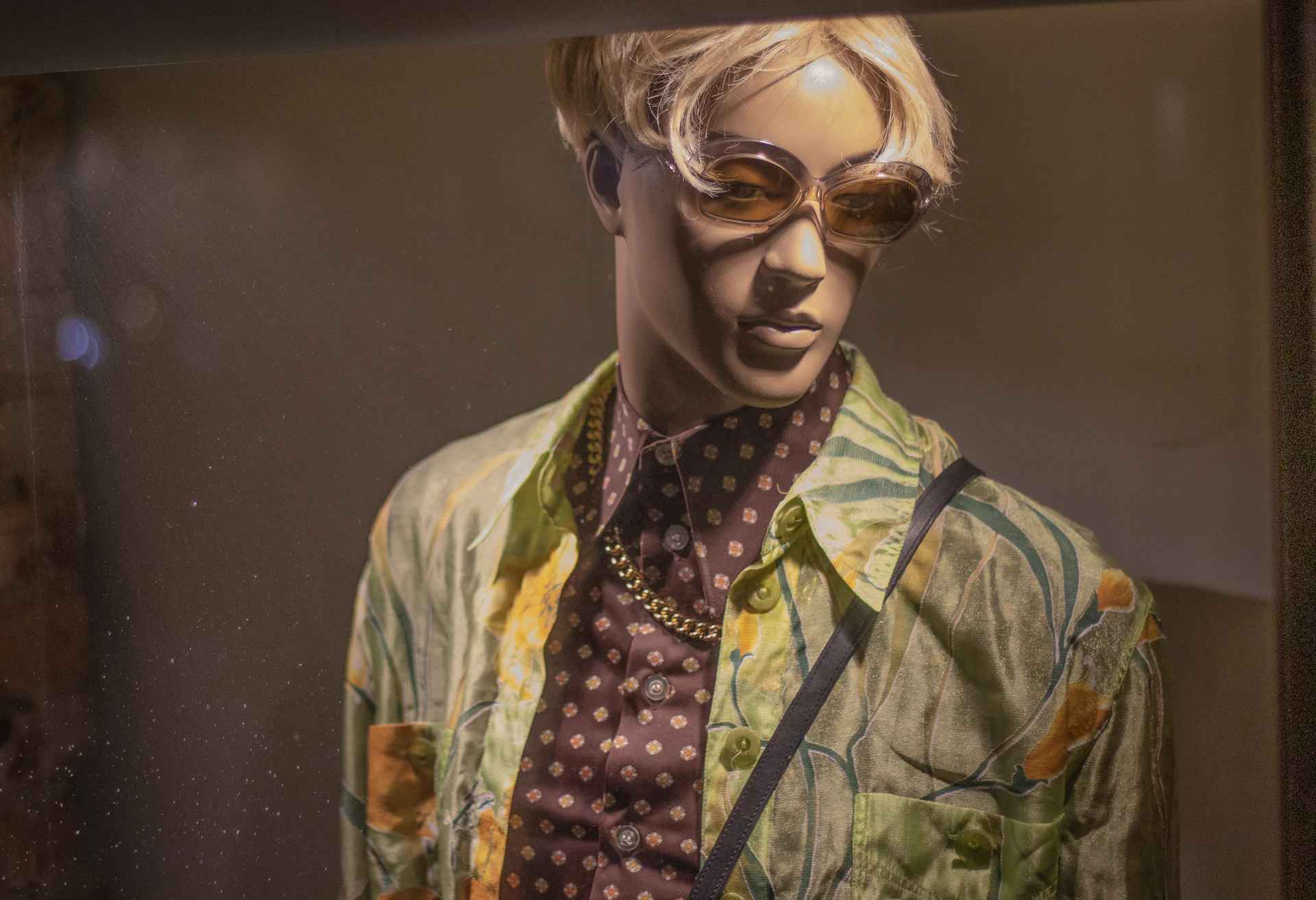 Close-up of a stylish summer dress displayed on a mannequin, surrounded by tropical plants and bright sunlight.