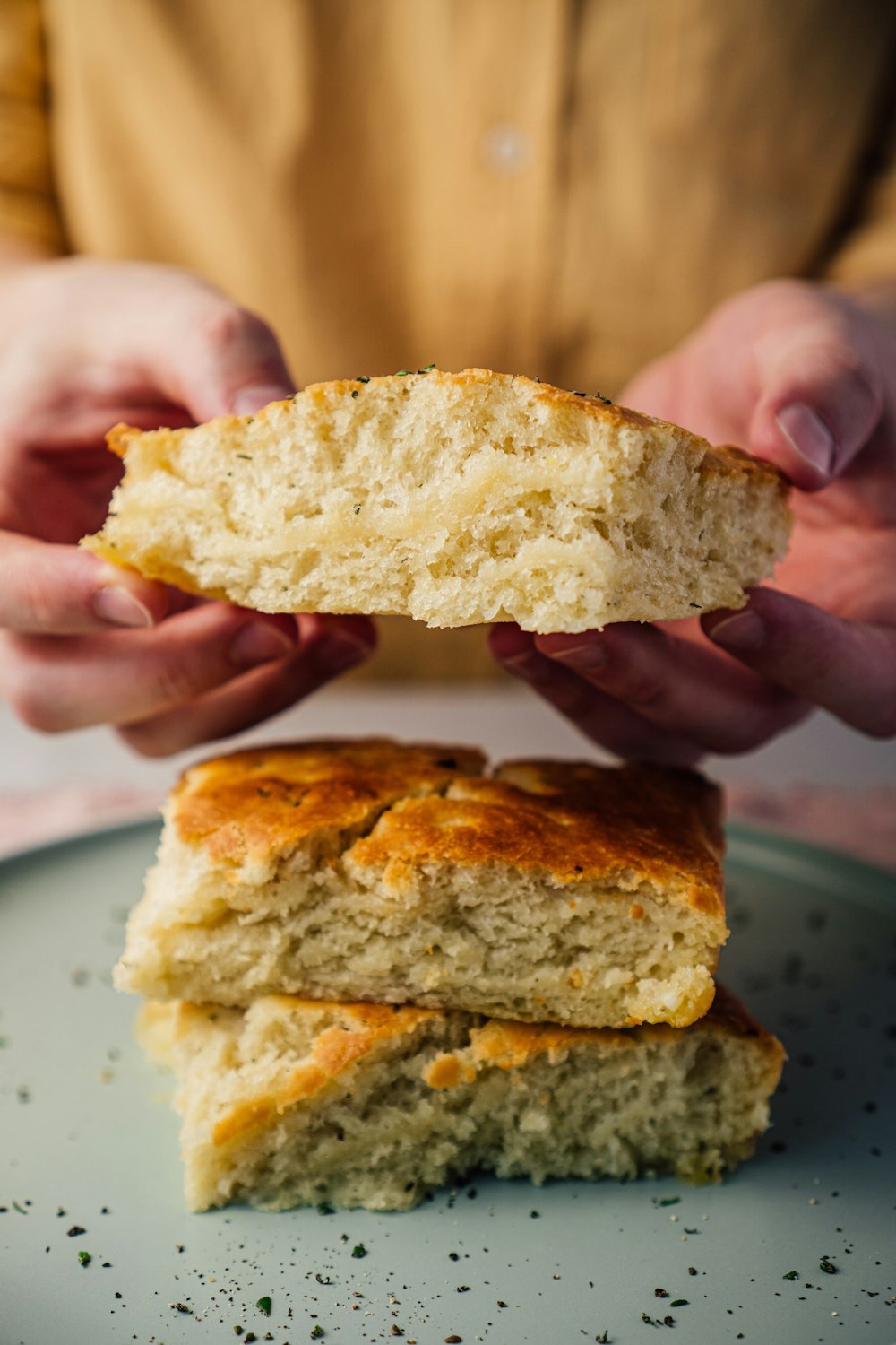 Persona che tiene il pane sul piatto di ceramica bianca