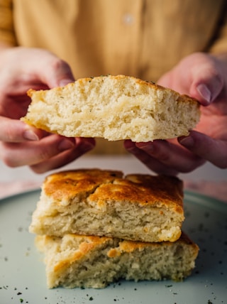 person holding bread on white ceramic plate