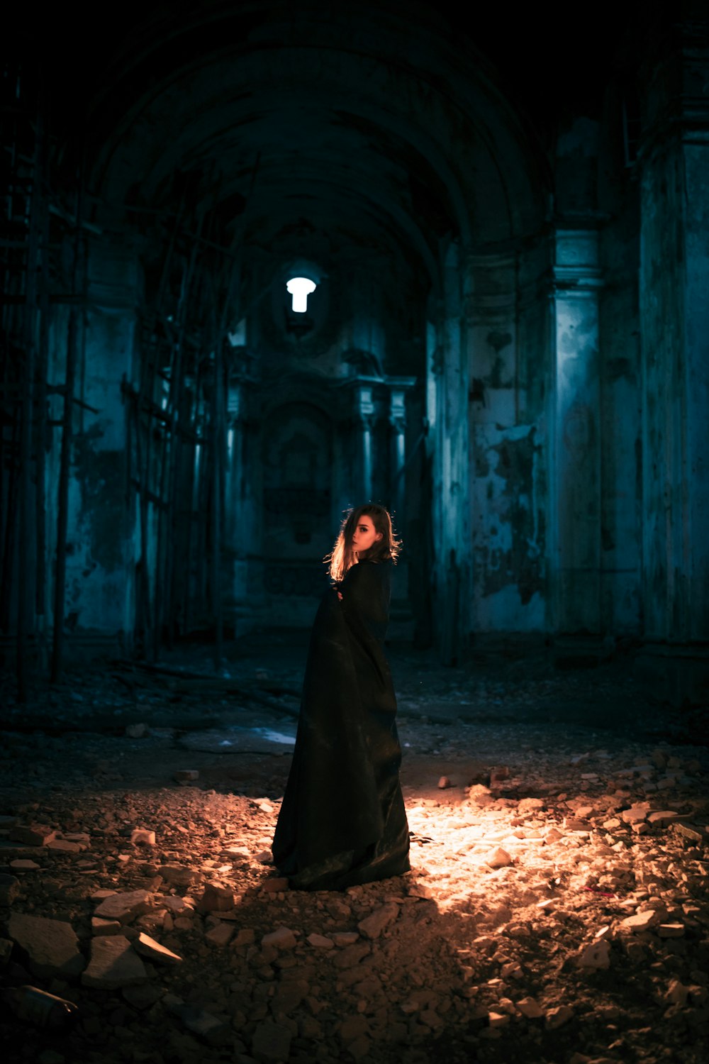 woman in black dress standing in the middle of a tunnel