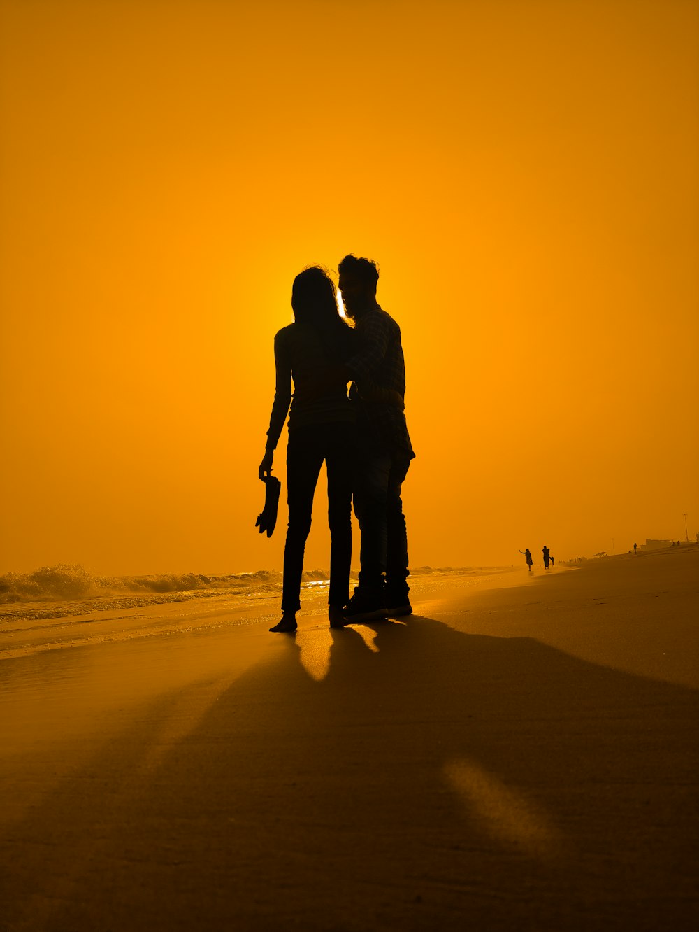 silhouette of couple standing on beach during sunset