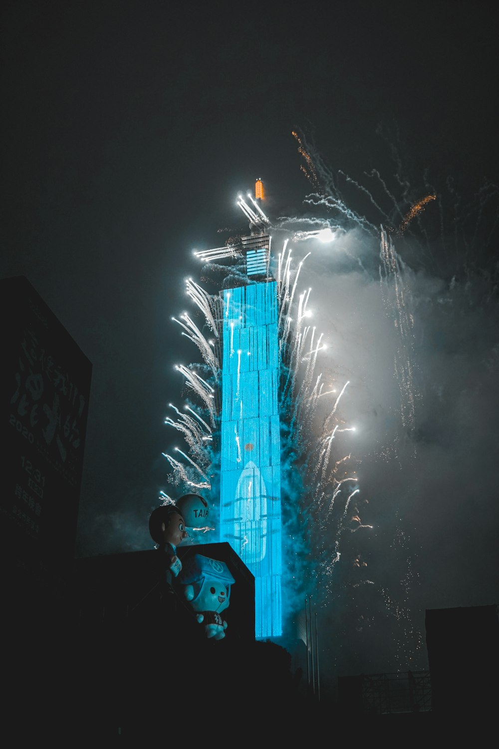 man in black jacket standing near white fireworks during night time