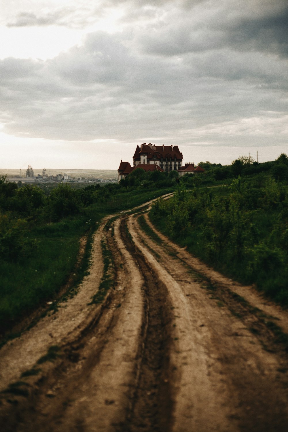 brown dirt road between green grass field during daytime