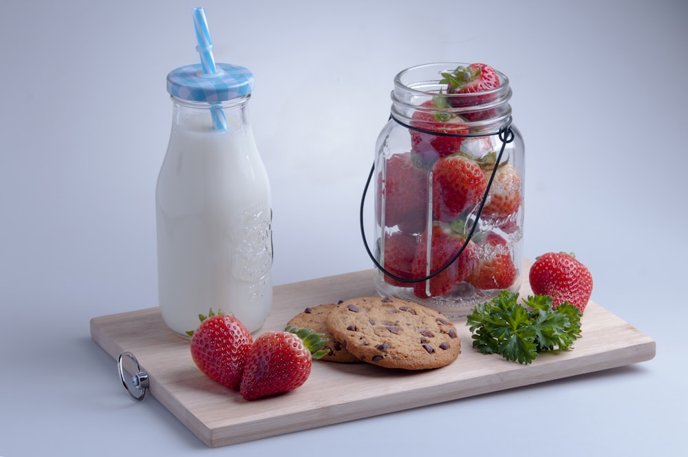 strawberries and blue straw in clear glass jar