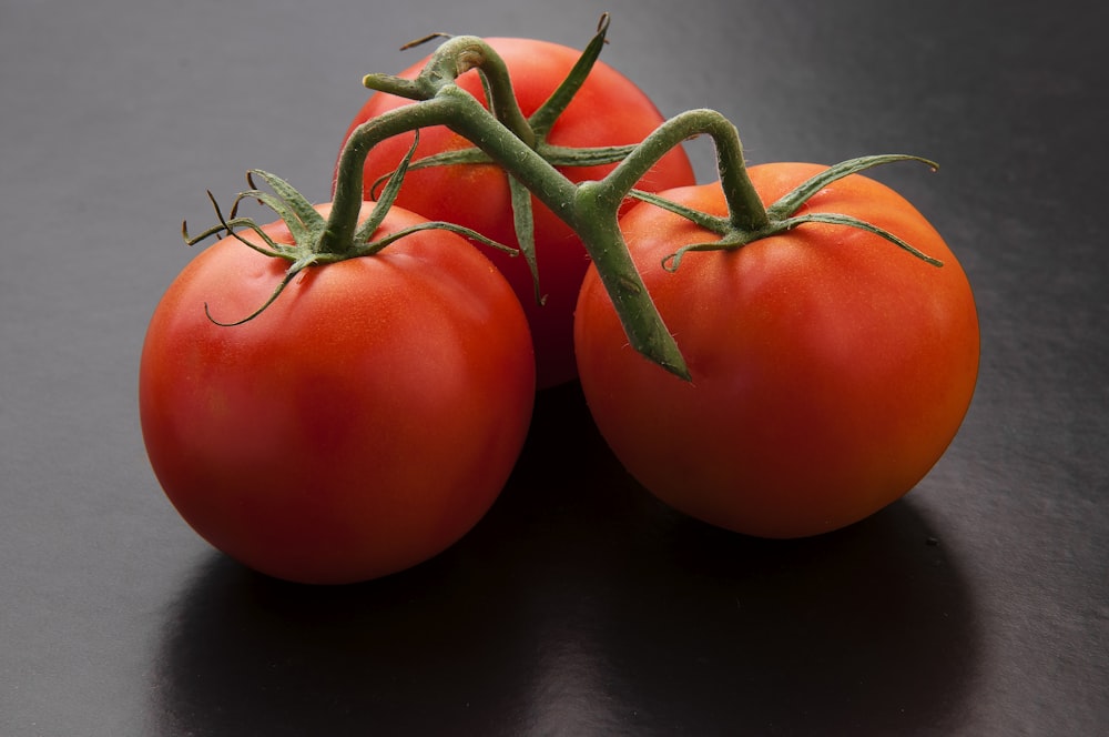 3 red tomato on black table