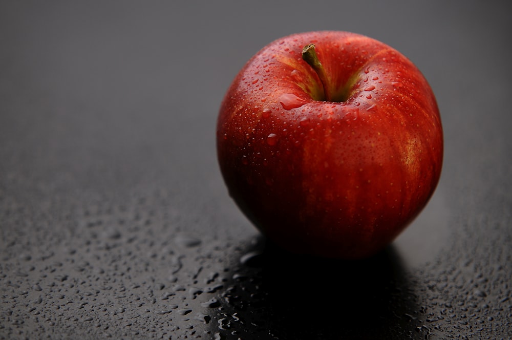 fruta da maçã vermelha na superfície preta