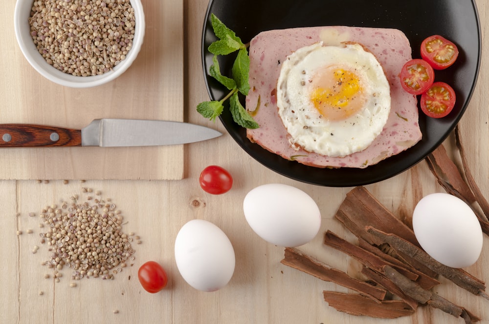 egg on black ceramic bowl beside stainless steel knife