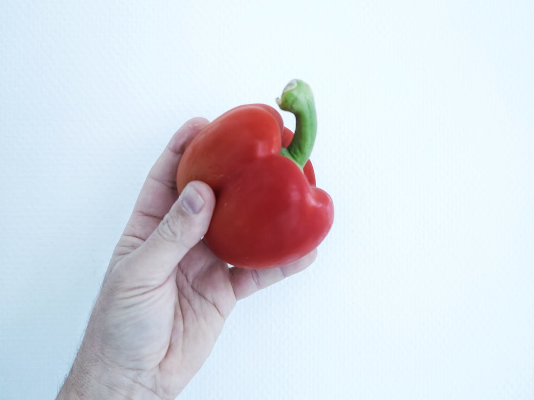 person holding red bell pepper