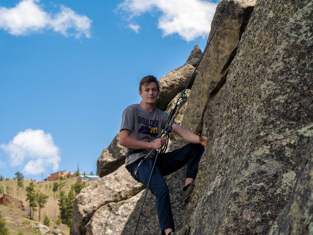 man in blue crew neck t-shirt and blue denim jeans standing on rock during daytime