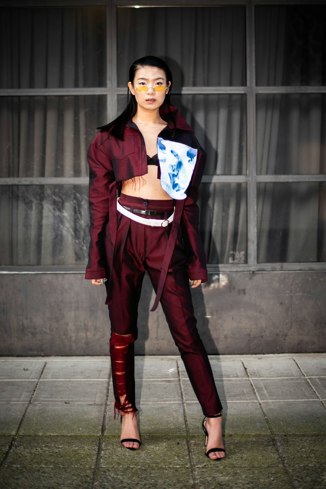 woman in red blazer and red pants standing beside gray wall