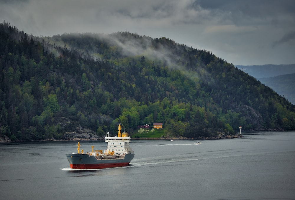 weißes und rotes Boot auf See in der Nähe der Berge tagsüber