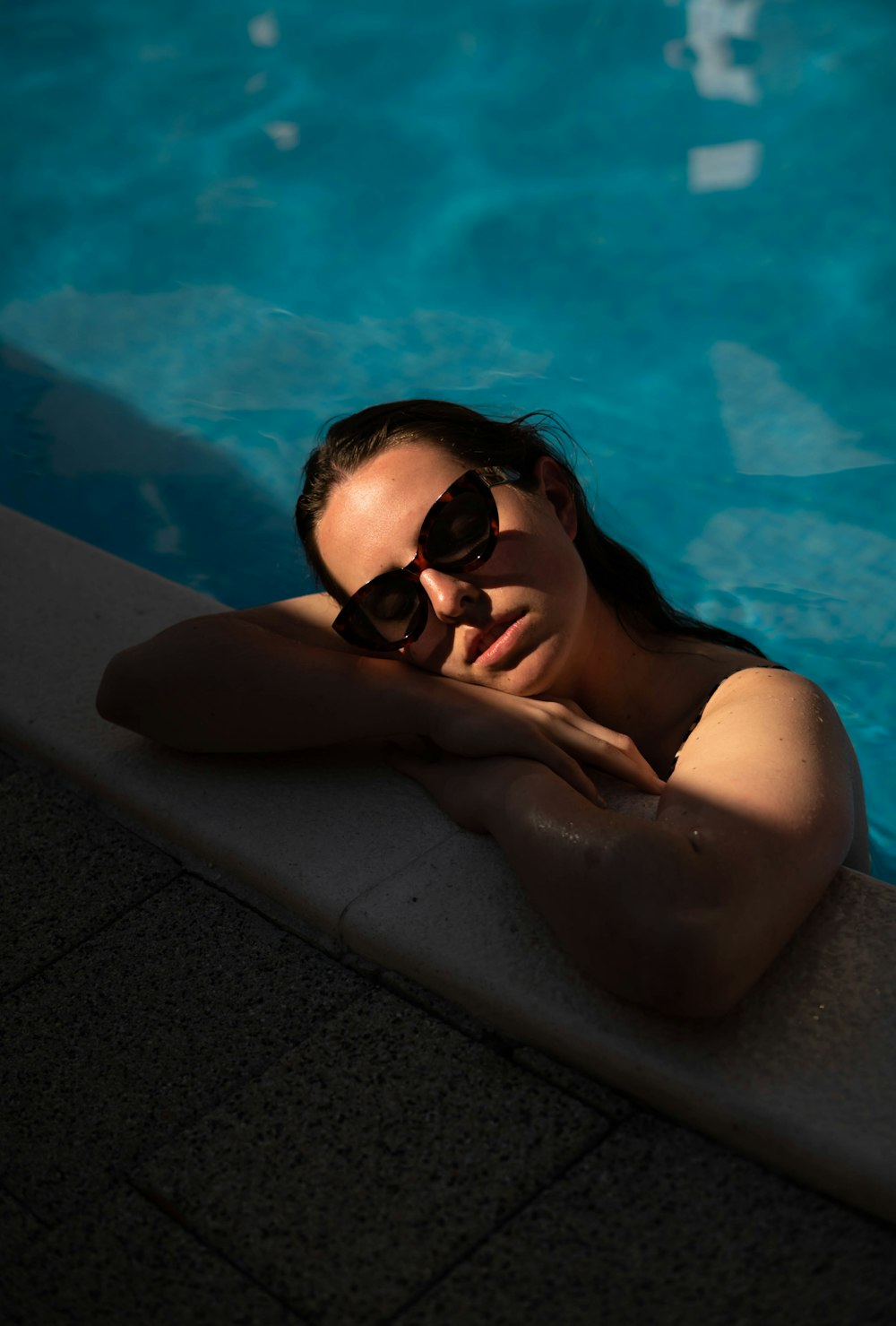 woman in black sunglasses lying on pool side