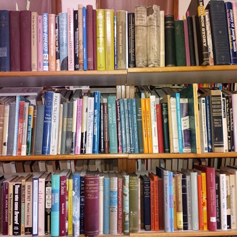 A wooden bookshelf filled with a variety of books, some leaning and some stacked, inviting exploration.