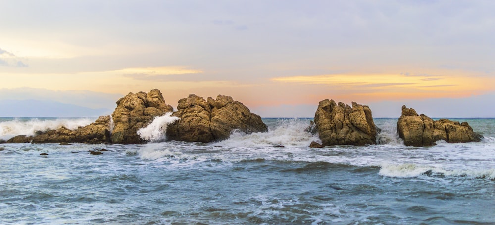 brown rock formation on sea during sunset