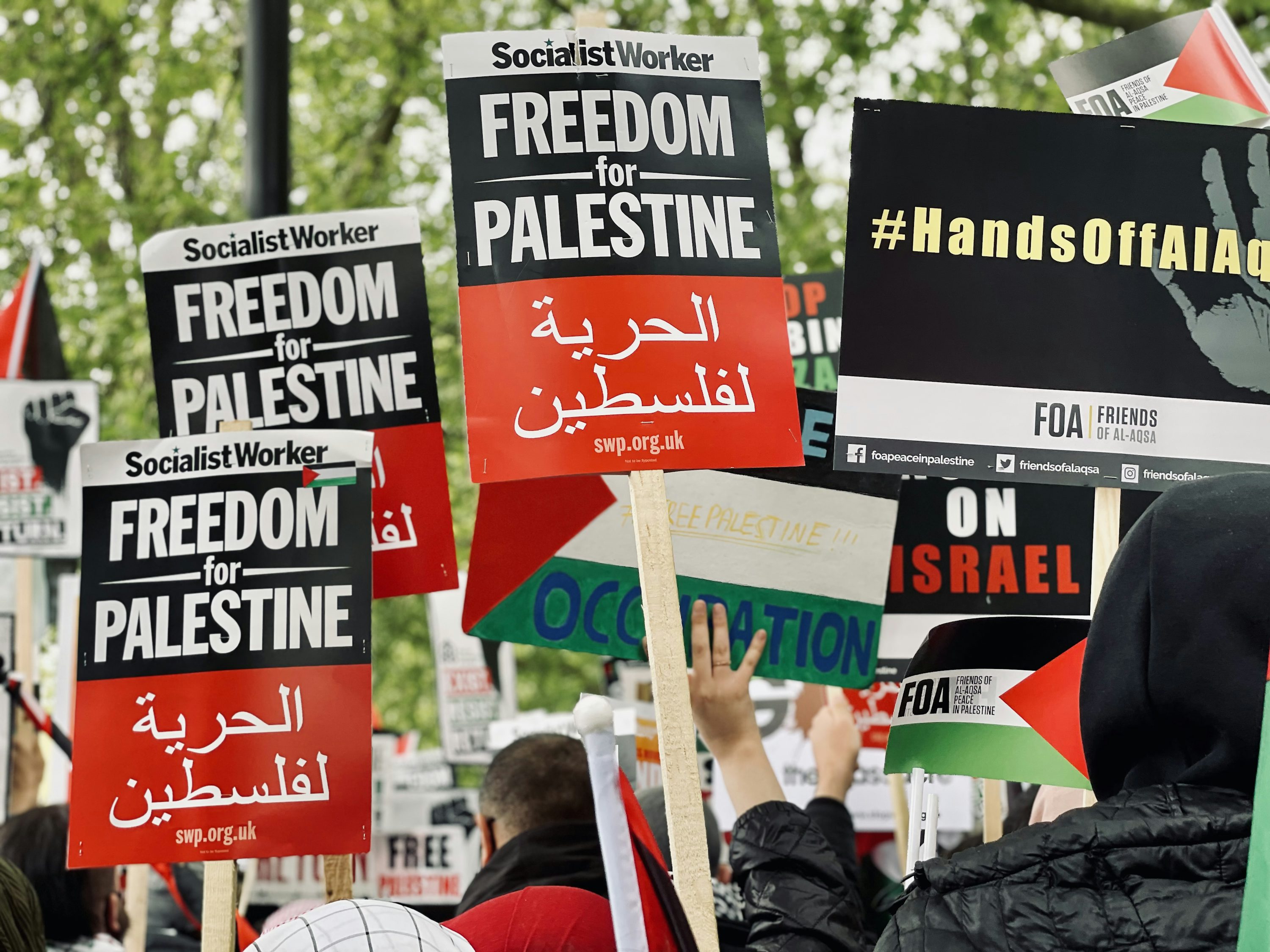 people holding red and white banner during daytime